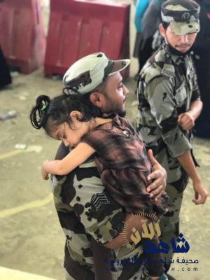 رجل أمن يحمل طفلة خلال قيام والدتها برمي الجمرة الصغرى